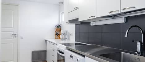 Cozinha moderna com armários brancos, pia de aço inoxidável e forno embutido.