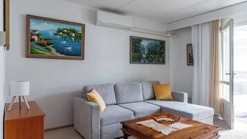 A modern living room with a grey sofa, a wooden coffee table, and two paintings on the wall.