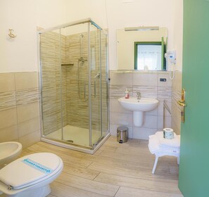 A bathroom with a glass-enclosed shower, a sink, and a toilet.
