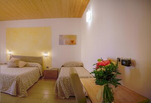 A hotel room with two beds, a wooden ceiling, a wall-mounted phone, and a vase with flowers.
