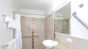 A bathroom with a shower, a sink, and a mirror.