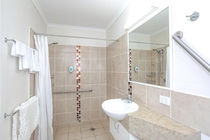 A bathroom with a shower, a sink, and a mirror.