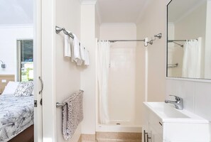 A bathroom with a bathtub, a shower, a sink, and a mirror.