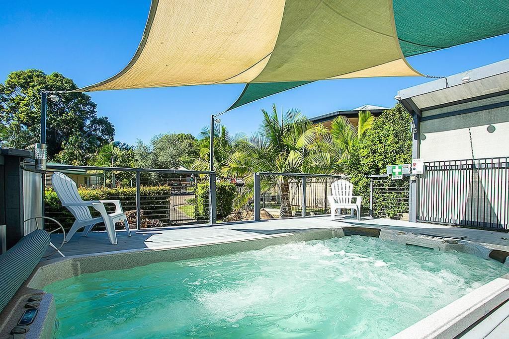 A swimming pool with a hot tub, surrounded by lounge chairs and a shaded area.
