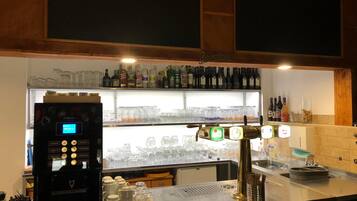 A bar area with a coffee machine, multiple taps, and shelves of bottles.