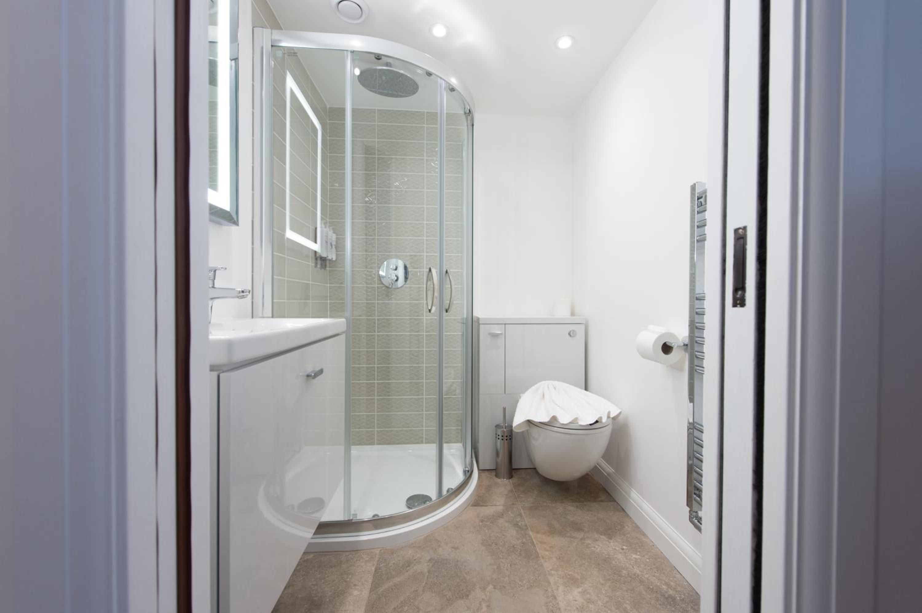 A modern bathroom with a glass-enclosed shower, a toilet, and a sink.