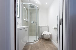 Un baño moderno con ducha acristalada, inodoro y lavamanos.