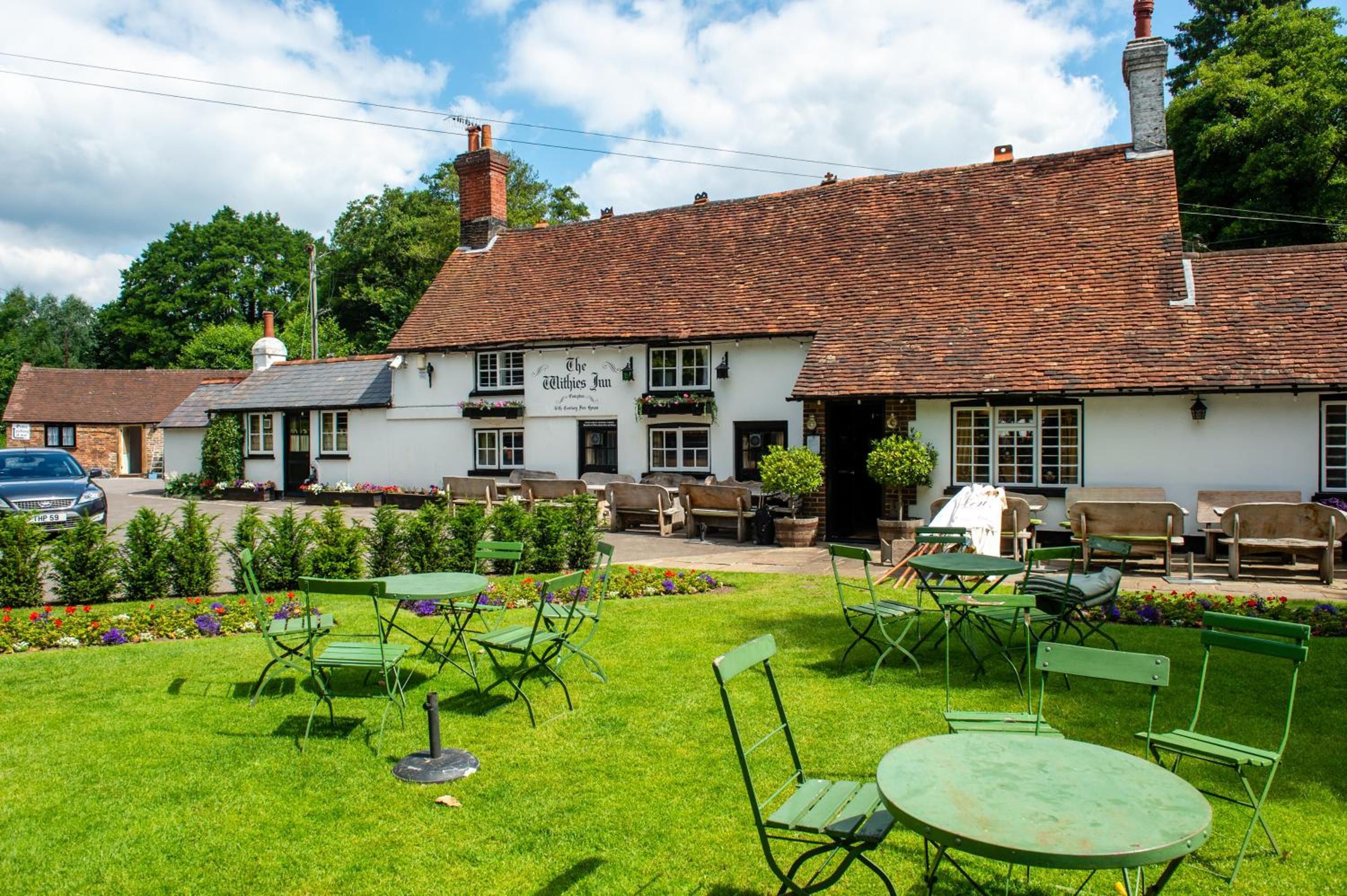 A traditional pub with outdoor seating and a well-maintained garden.
