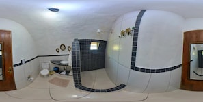 A bathroom with a white and black tiled design, a toilet, a sink, and a shower area.