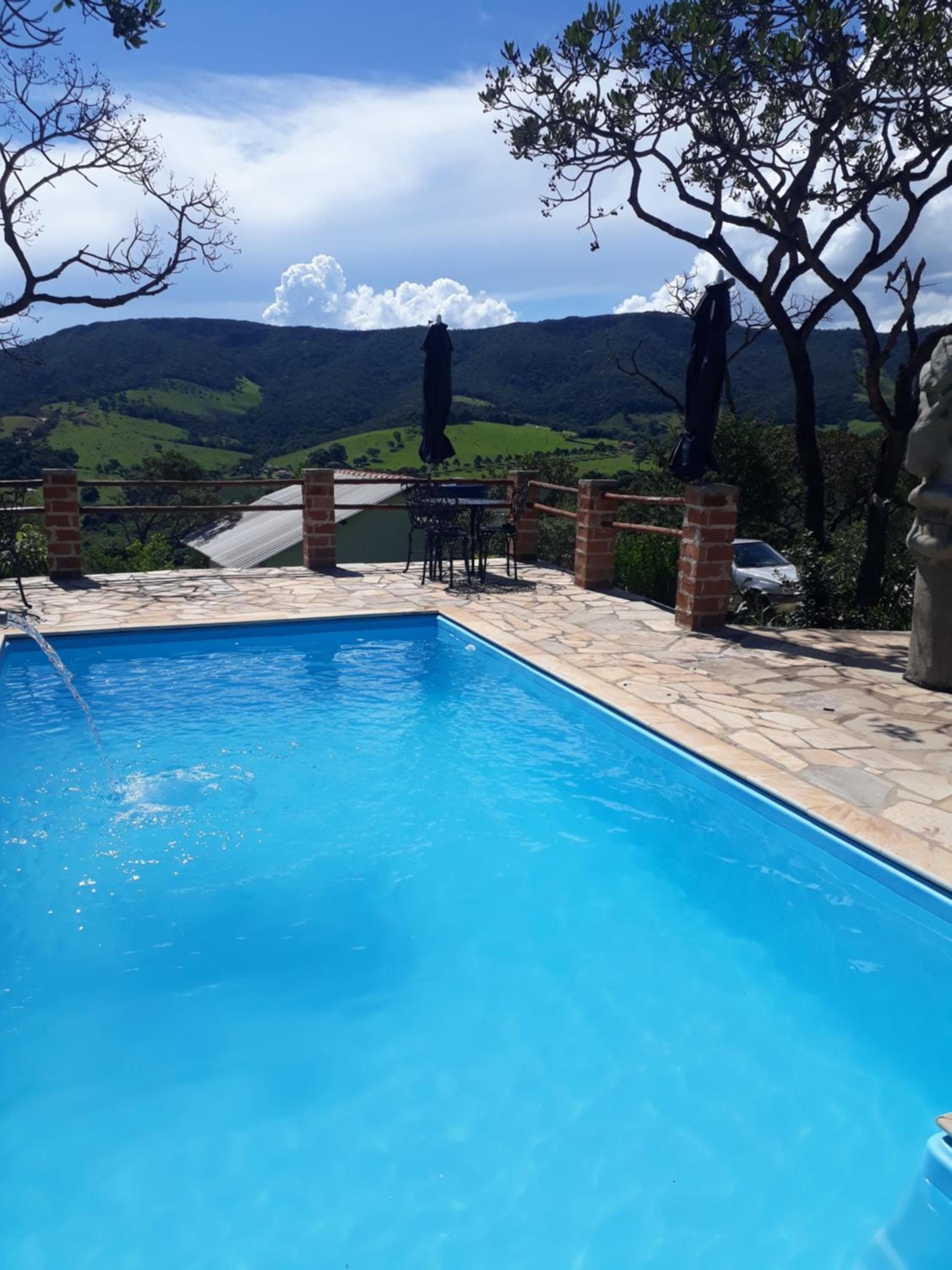 A swimming pool with a view of green hills and a clear sky.