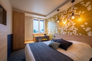 A hotel room with a bed, a desk, and a window. - Sous Les Pins (Etoile-sur-Rhone)