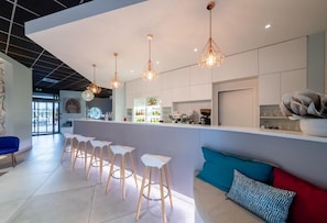 A modern bar area with white stools, a bar counter, and pendant lighting. - Sous Les Pins (Etoile-sur-Rhone)