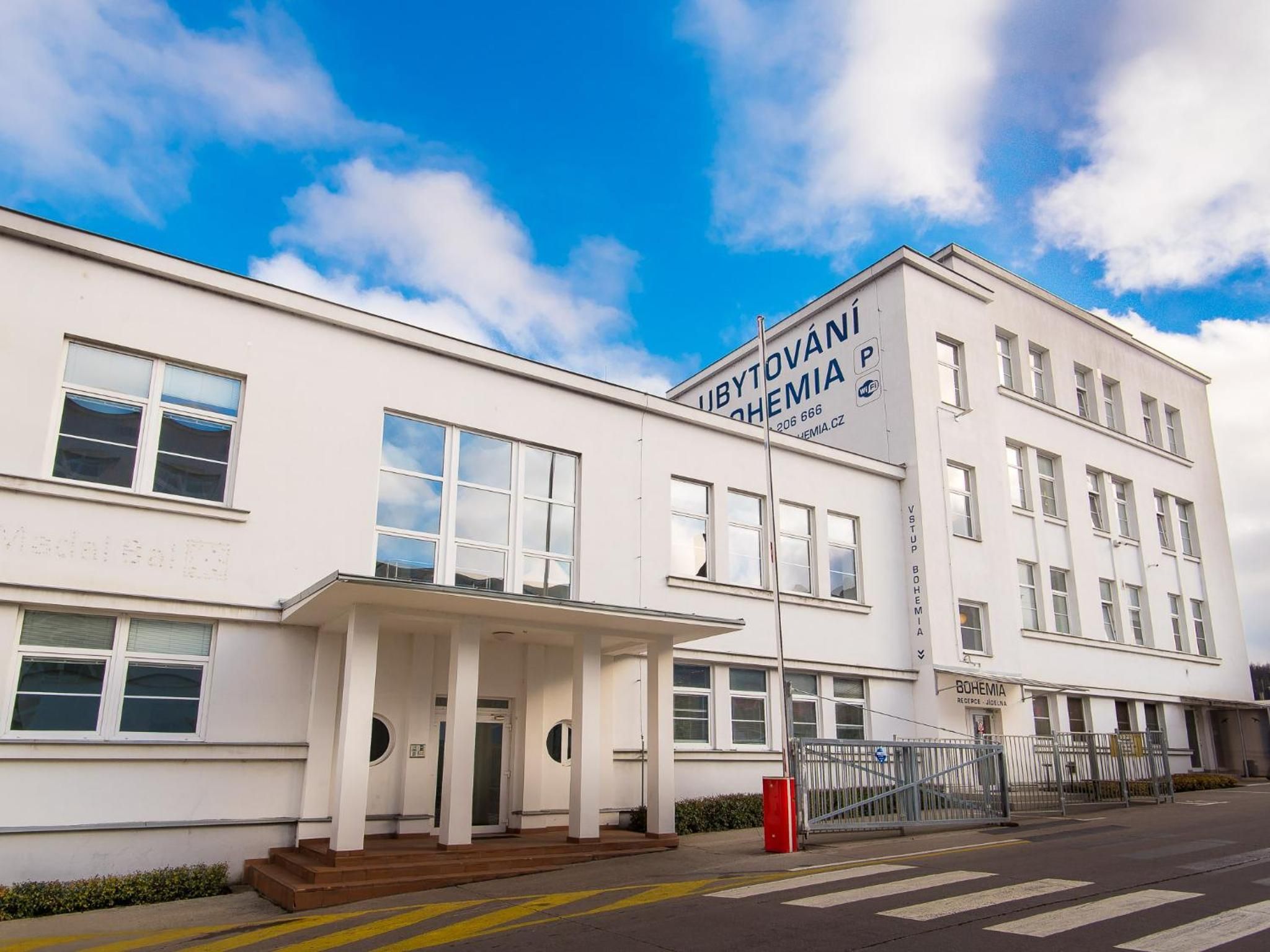A white building with multiple windows and a sign that reads 'UBYTOVANI BOHEMIA'.
