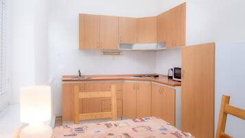 Una cocina compacta con armarios de madera, un microondas y un lavamanos.