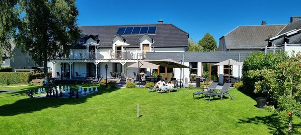A two-story building with a covered patio area, outdoor seating, and a well-maintained lawn.