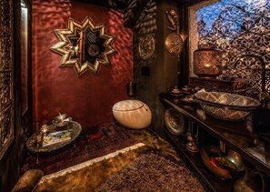Quarto com espelho em formato de estrela, uma tigela branca e bandejas de metal decoradas.