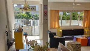 A dining area with a wooden table, a vase of flowers, and a view of the outside through a glass door. - Eco Isla Guesthouse (Florianópolis)