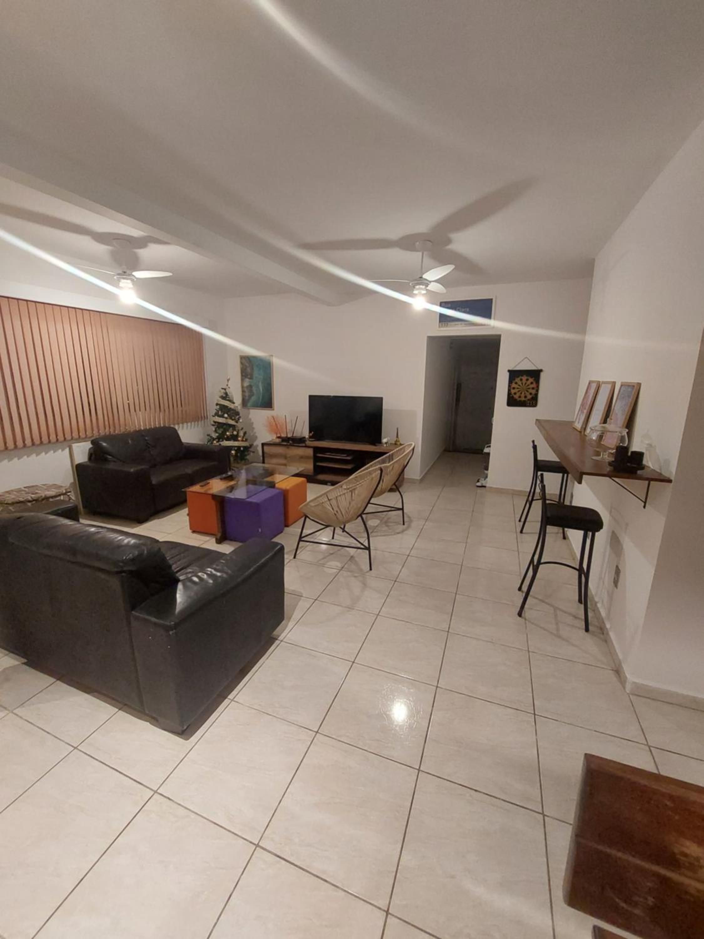 Ein modernes Wohnzimmer mit einer Couch, einem Fernseher und einem Essbereich mit Stühlen.