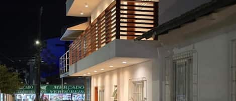 Un edificio moderno de dos pisos con terraza de madera y mobiliario exterior.