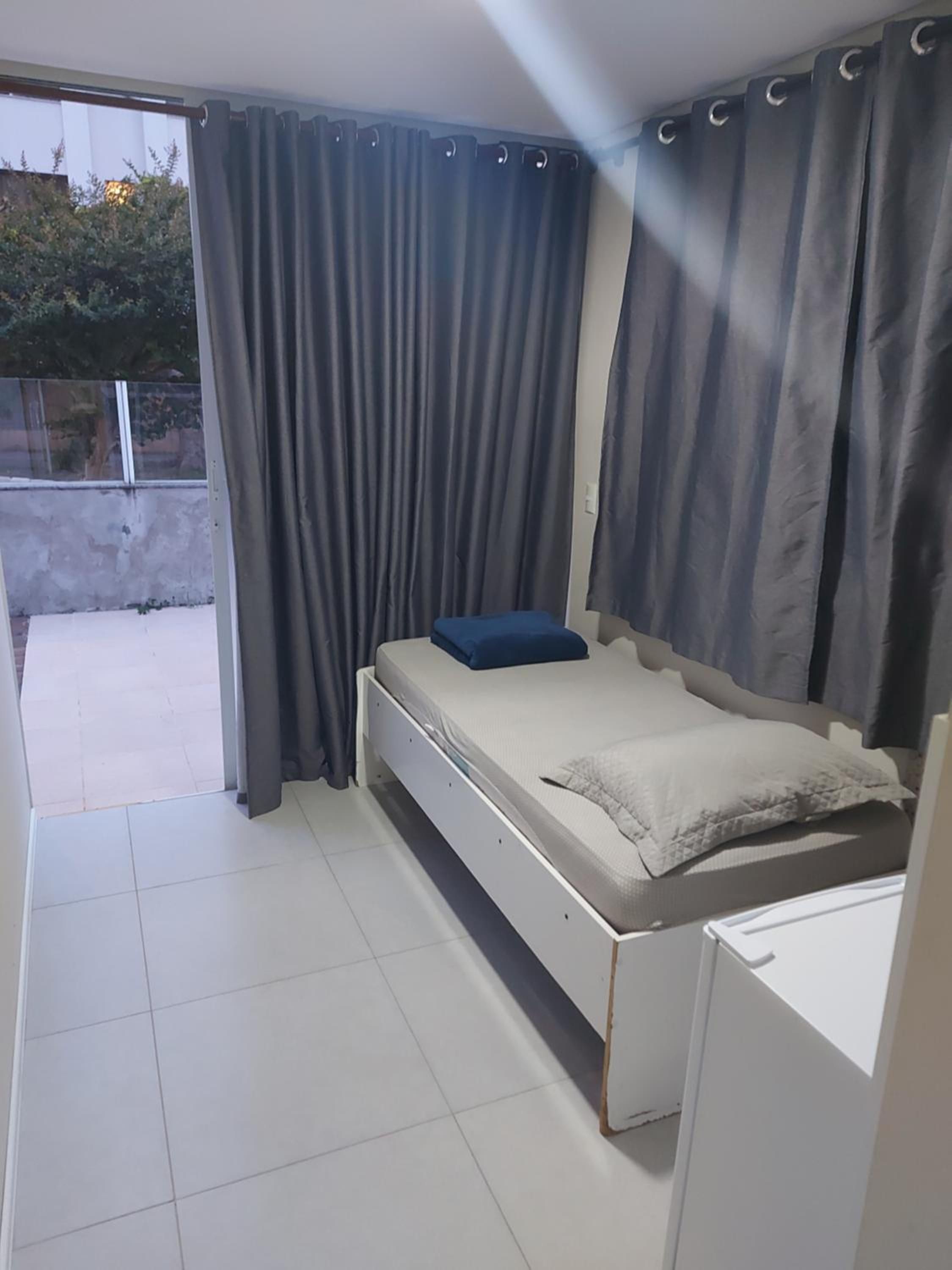 Un dormitorio con cama, cortinas y vistas al exterior.
