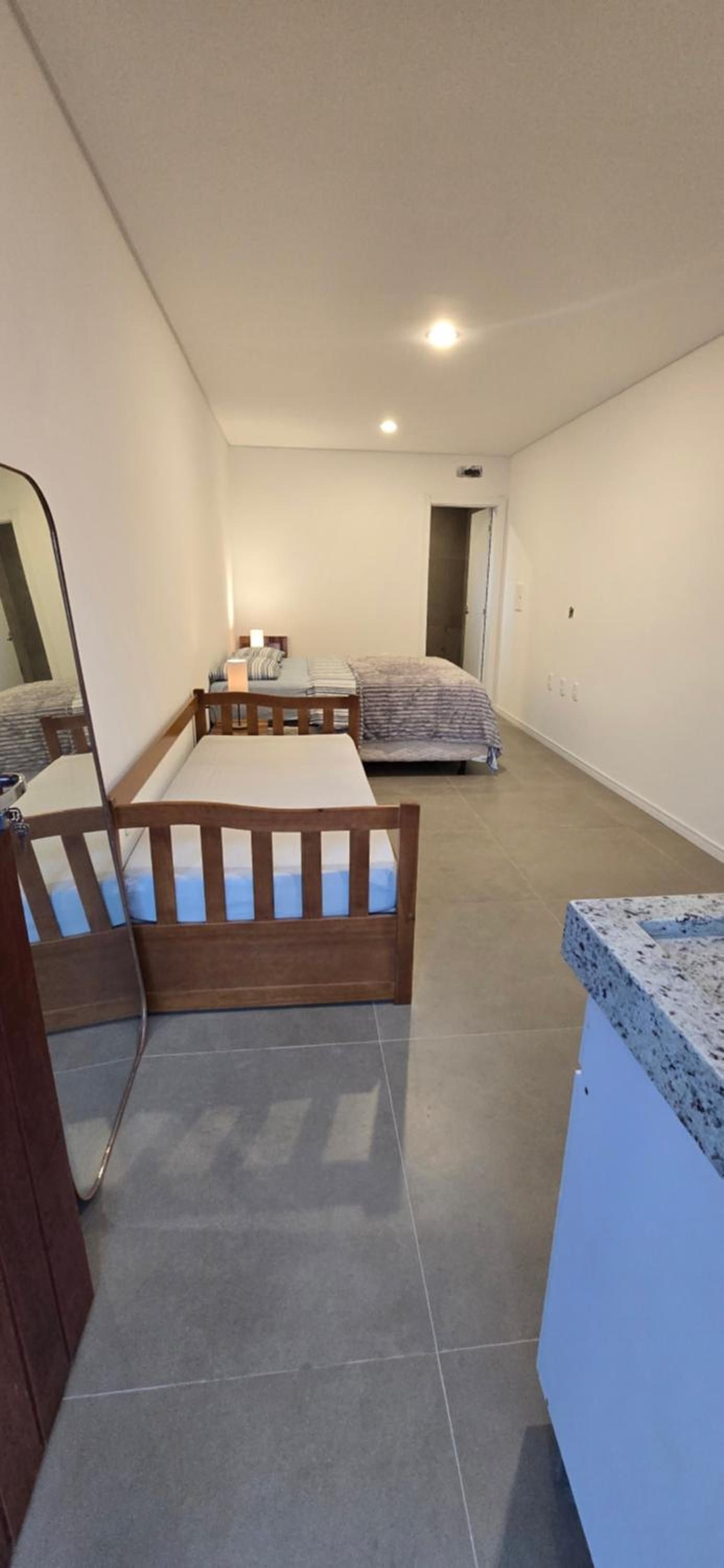 A bedroom with a bed, a bedside table, and a mirror.