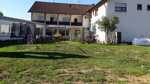 Ein Wohngebäude mit überdachter Terrasse, Schaukel und Gasflasche.