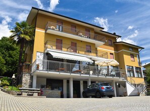 A multi-story building with balconies, a covered entrance, and a car parked in front. - Albergo Ristorante Innocenti (Ardenno)