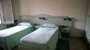 A room with two single beds, a nightstand, and a small table. - Albergo Del Po (Parma)