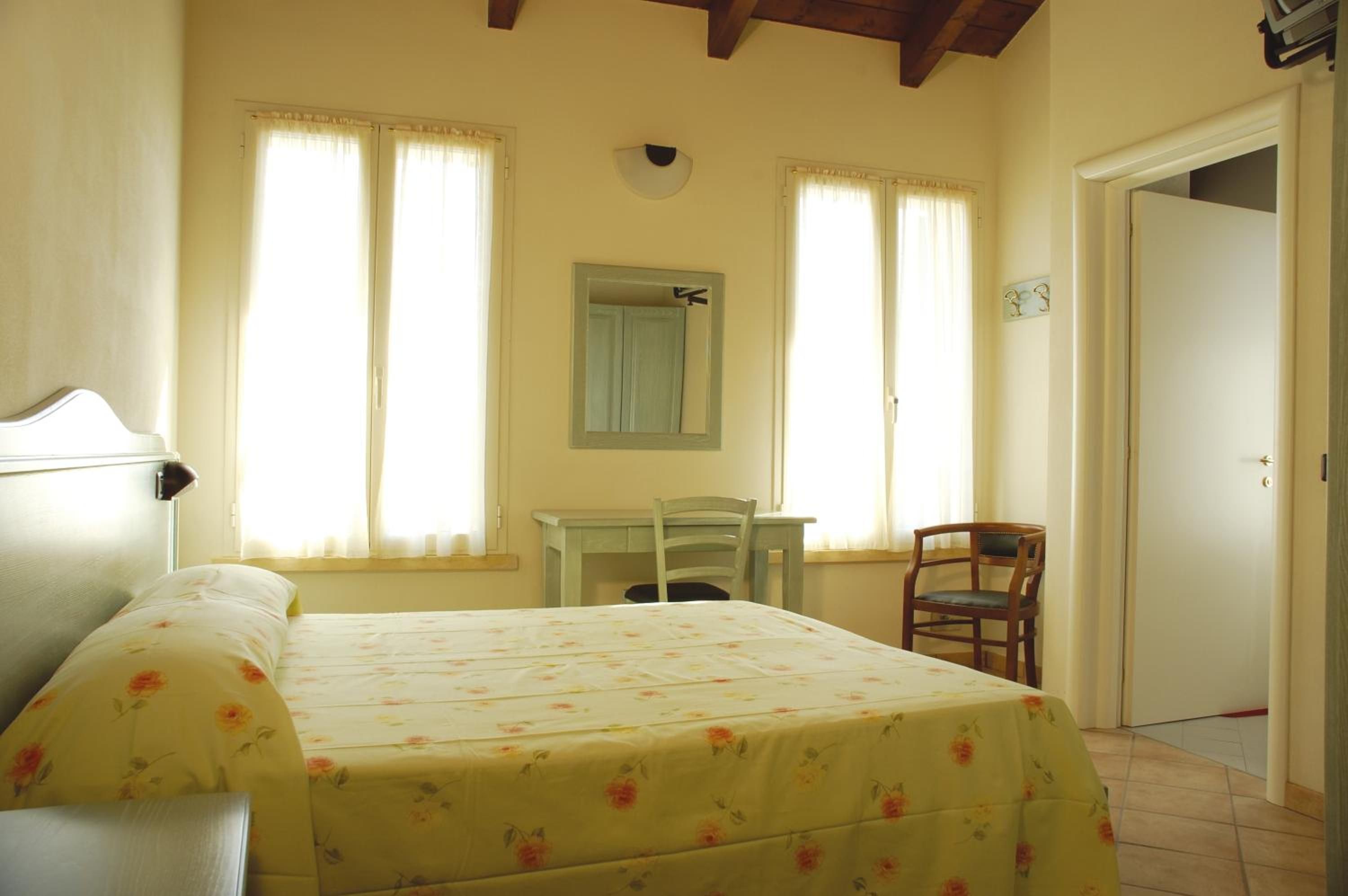 A bedroom with a bed, a desk, a chair, and a door.