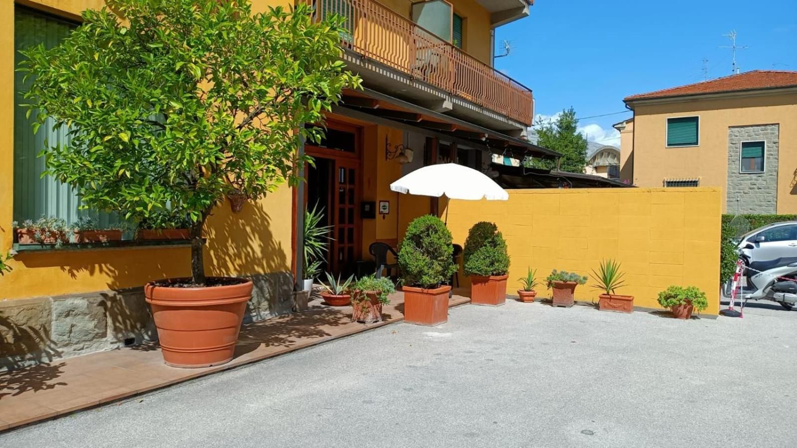 Un bâtiment jaune avec un balcon, des plantes en pot et une voiture garée.