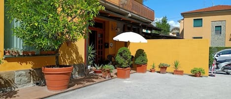 Un edificio amarillo con balcón, plantas en macetas y un coche estacionado.