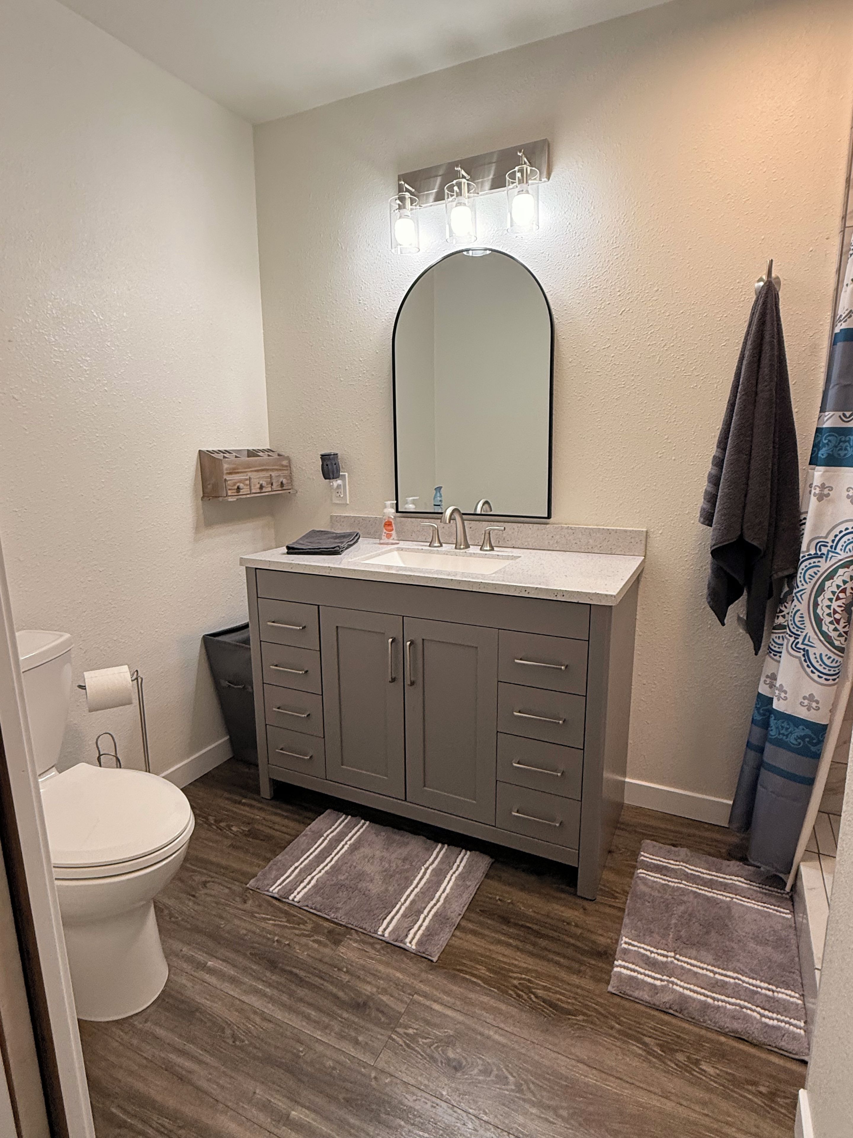 A bathroom with a white toilet, a vanity with a mirror, and a shower curtain.