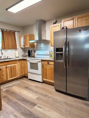 A kitchen with wooden cabinets, a stainless steel refrigerator, a built-in oven, and a range hood.