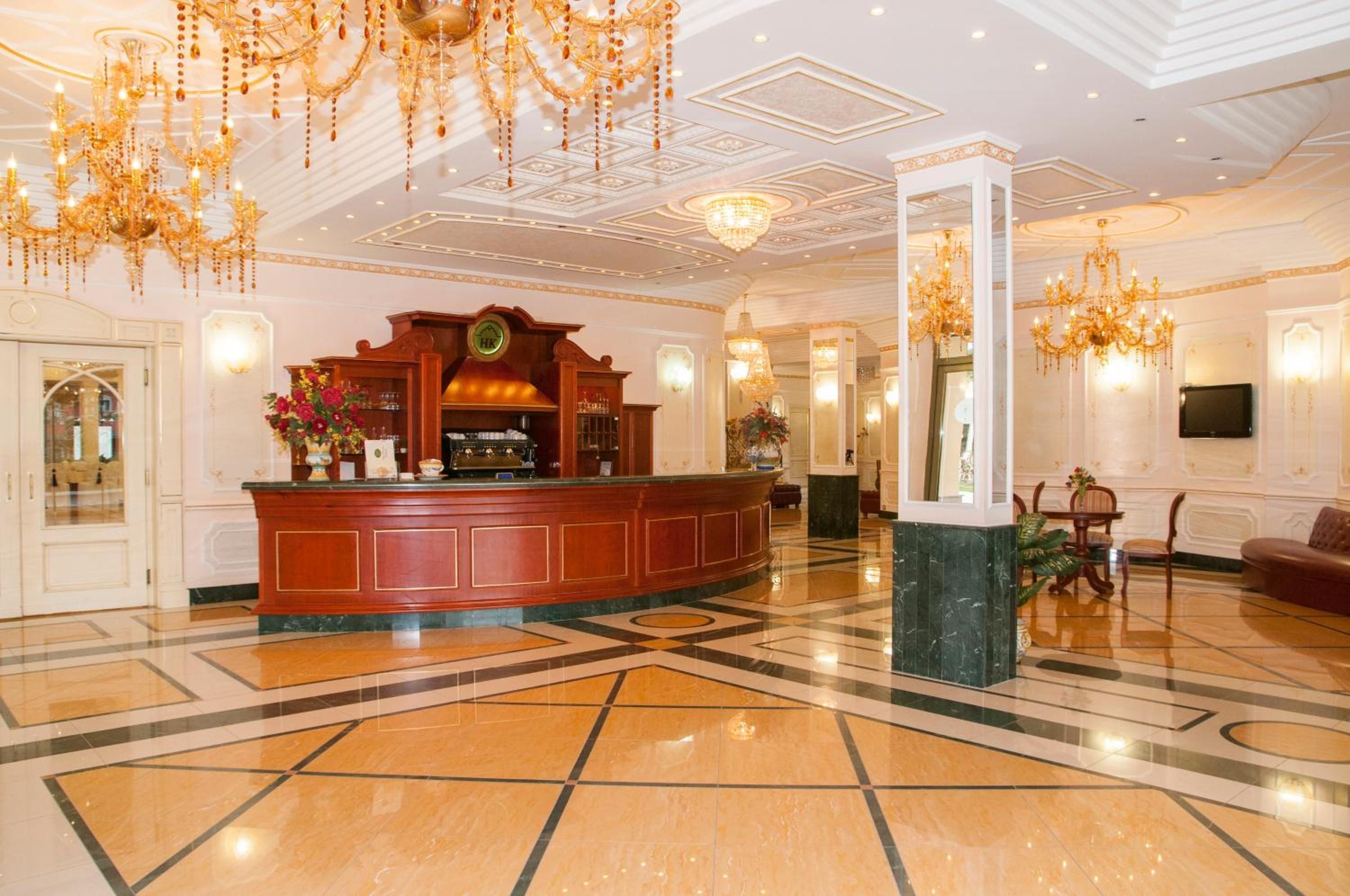 Eine Lobby mit einer Rezeption, Kronleuchtern und einem Check-in-Schalter.