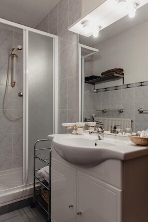 A modern bathroom with a walk-in shower, a vanity with a sink, and a mirror above the mirror. - Hôtel Les Charmilles De Mormal (Landrecies)