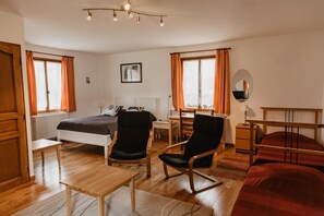 A hotel room with a bed, two chairs, a table, a desk, a mirror, and a window with curtains. - Hôtel Les Charmilles De Mormal (Landrecies)