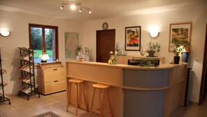 Una cocina con una isla central, taburetes de bar, una estantería y un mapa en la pared.