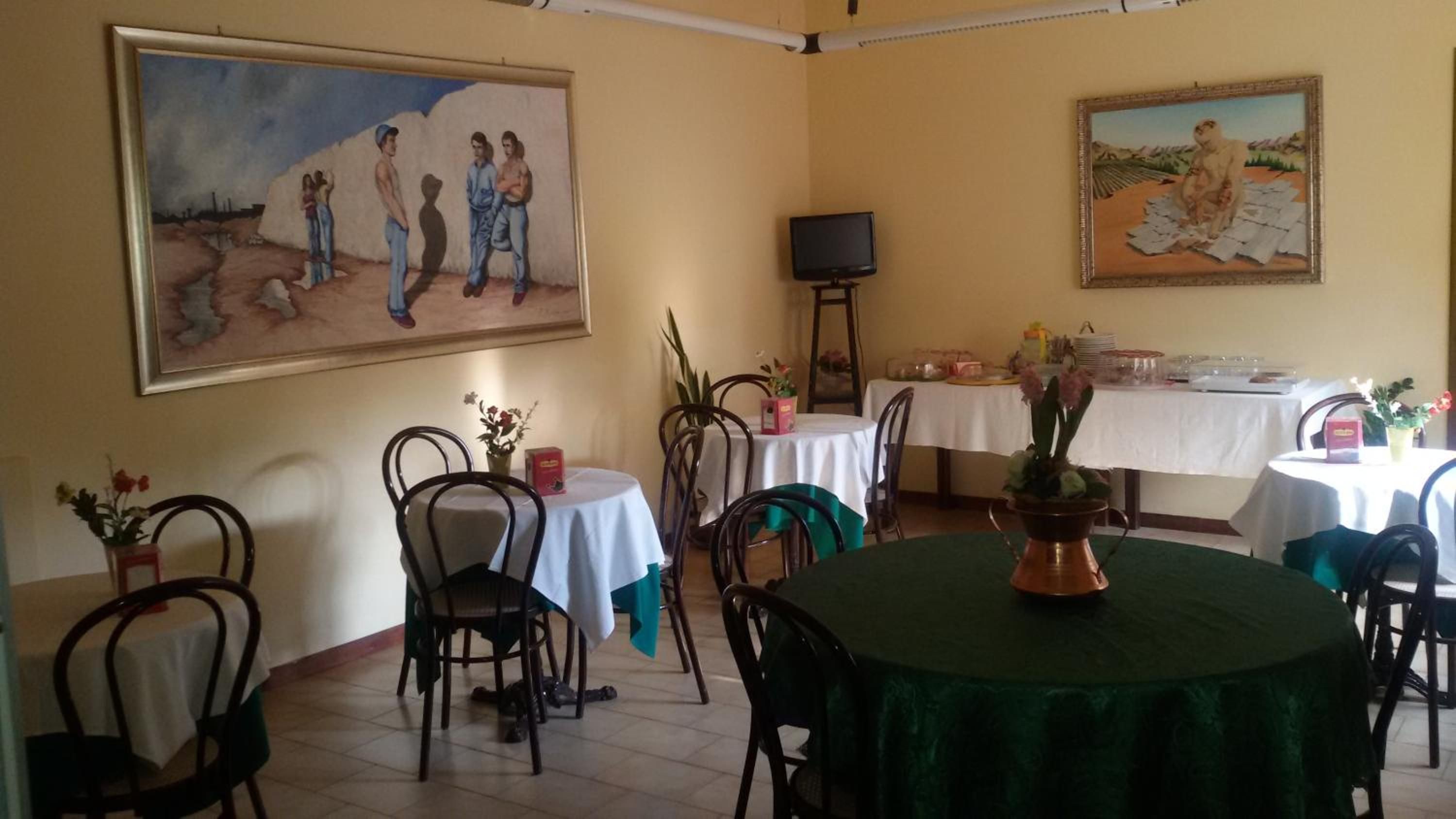 Zona pranzo con tavoli, sedie, quadri e televisore.