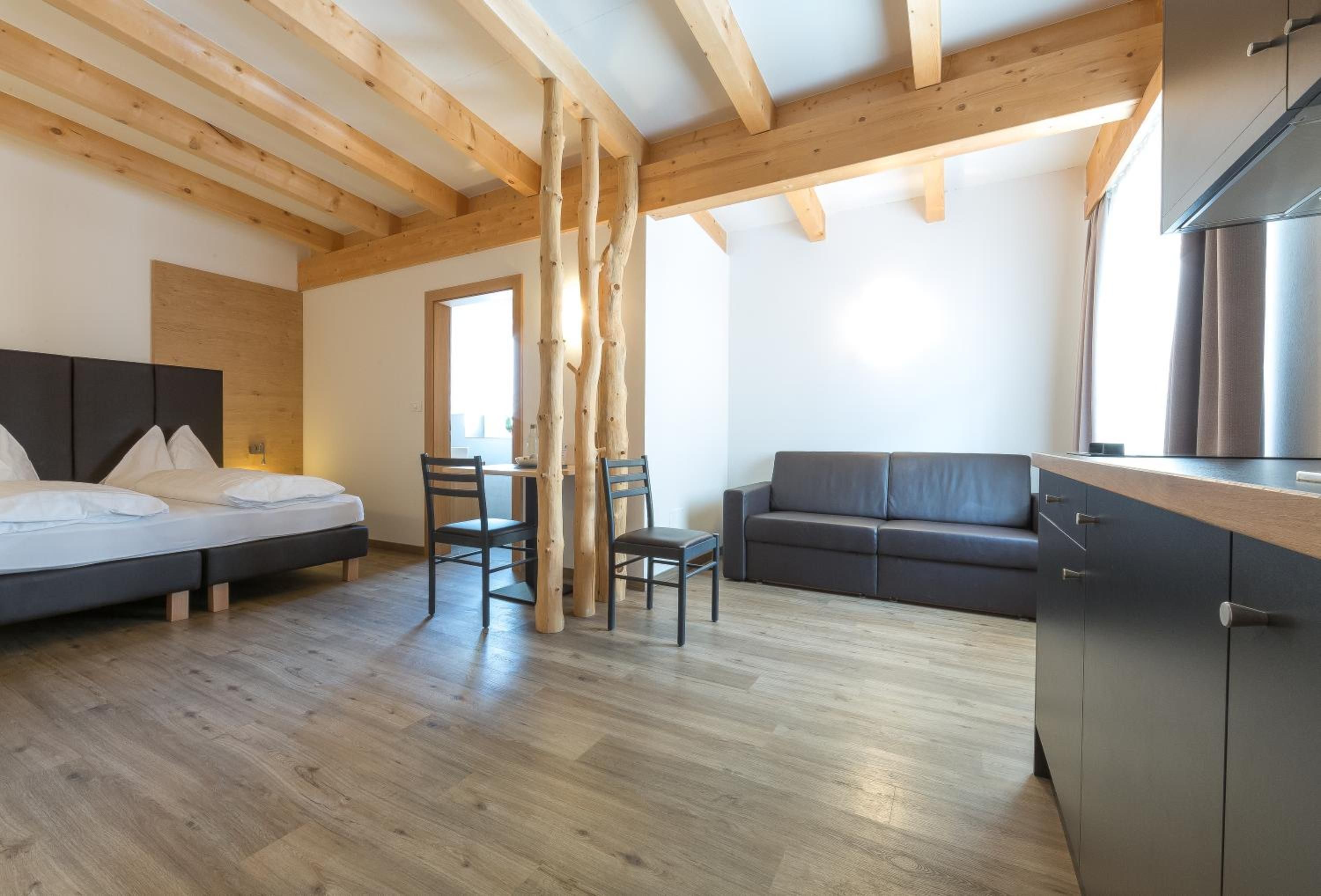 Una camera moderna con un letto, un divano, un tavolo da pranzo con sedie e un angolo cottura.