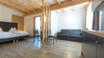 Una camera moderna con un letto, un divano, un tavolo da pranzo con sedie e un angolo cottura.
