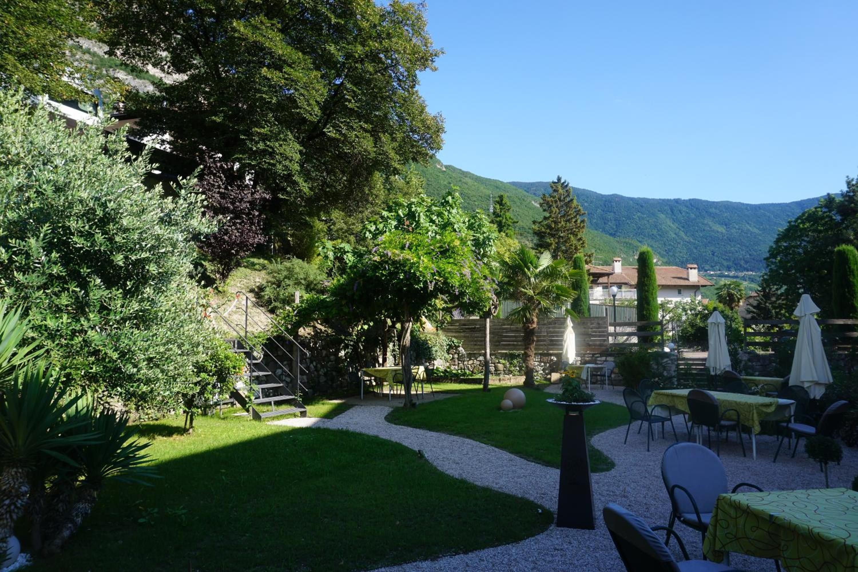 A garden with a gravel path, outdoor seating, and a view of a mountain.