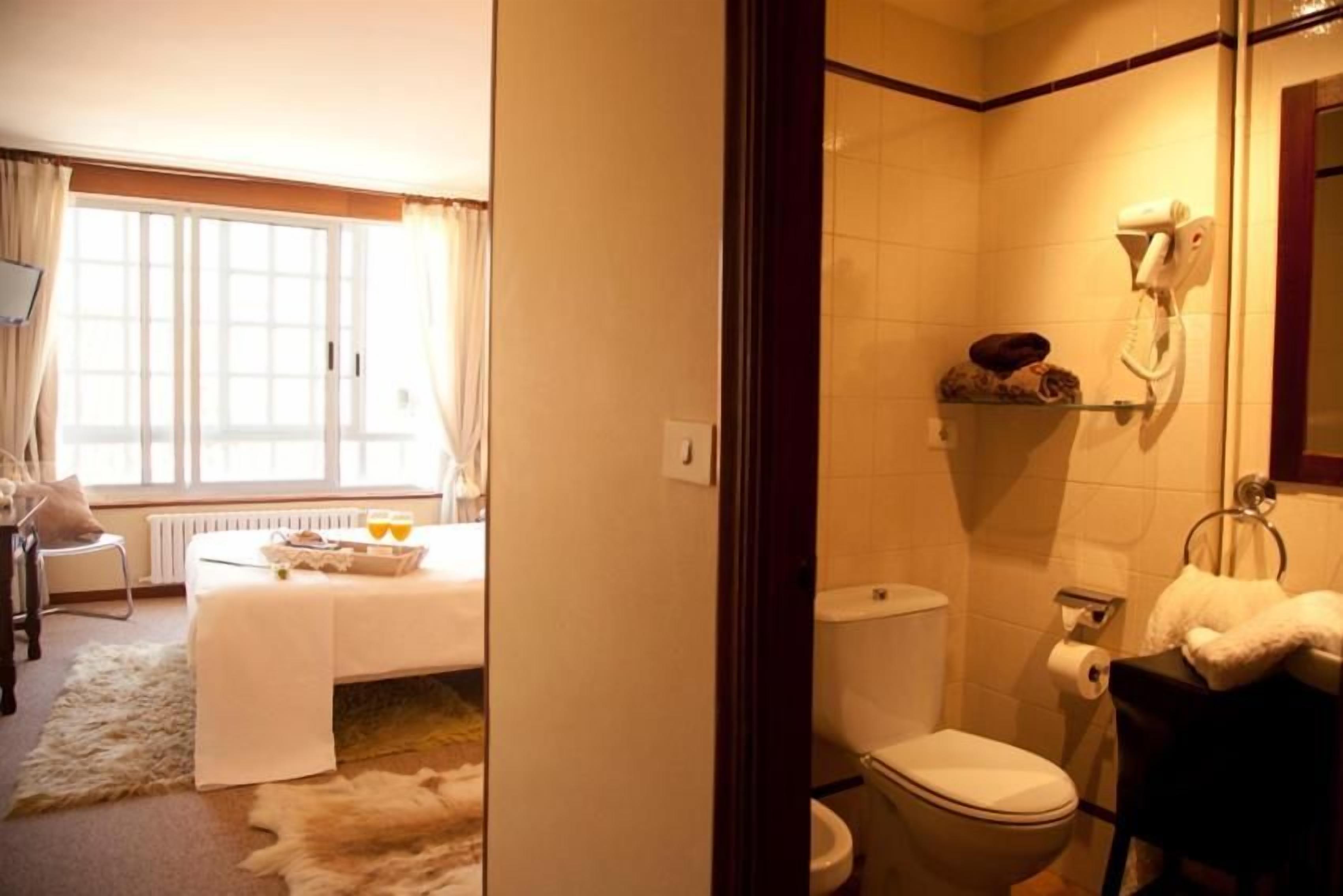 A hotel room with a bed, a bathroom, and a view of the outdoors.