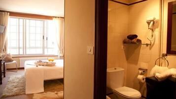 A hotel room with a bed, a bathroom, and a view of the outdoors.