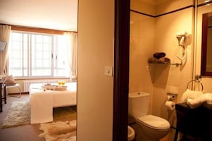 Habitación de hotel con cama, baño y vistas al exterior.