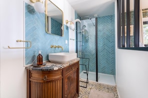 Un baño con tocador, espejo, cabina de ducha y zanjas de baldosas en las paredes.