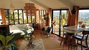 Una habitación amplia con un gran ventanal, un comedor y un espacio de estar con vistas.