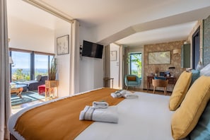 Una habitación de hotel con cama, escritorio, silla, televisión y vistas al exterior.