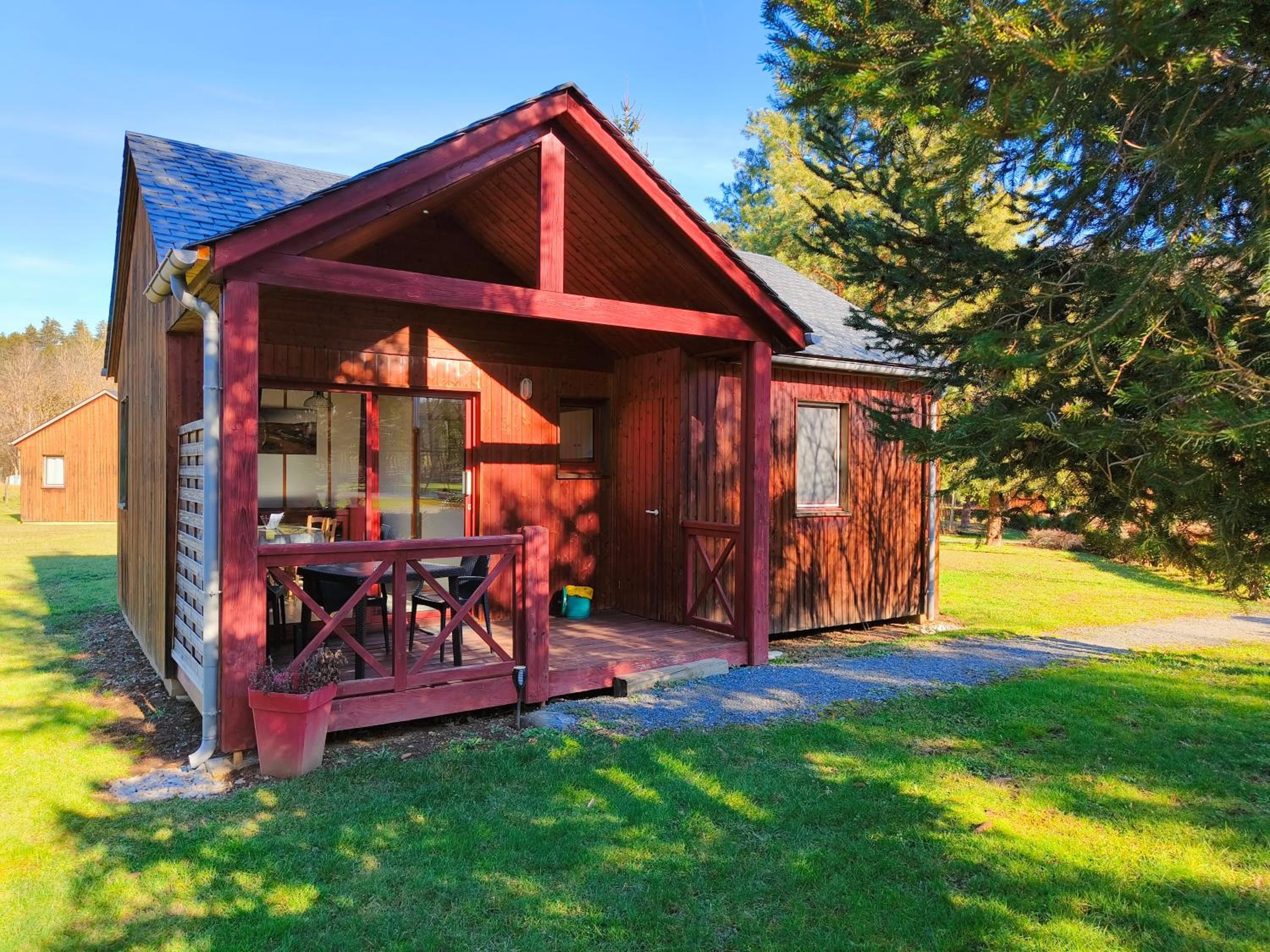 A wooden cabin with a porch, a dining area, and a garage.