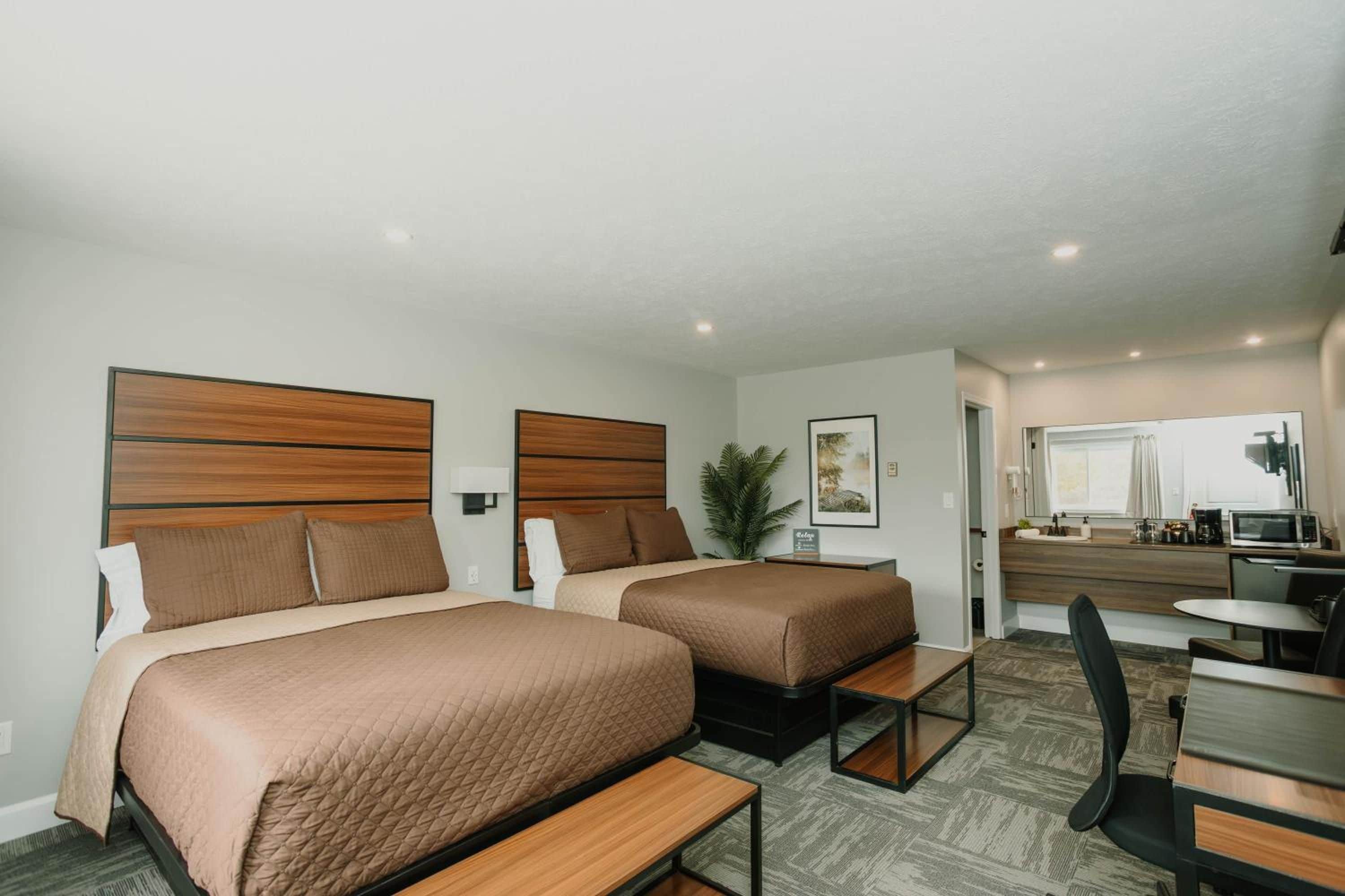 A hotel room with two beds, a kitchenette, and a small dining area.