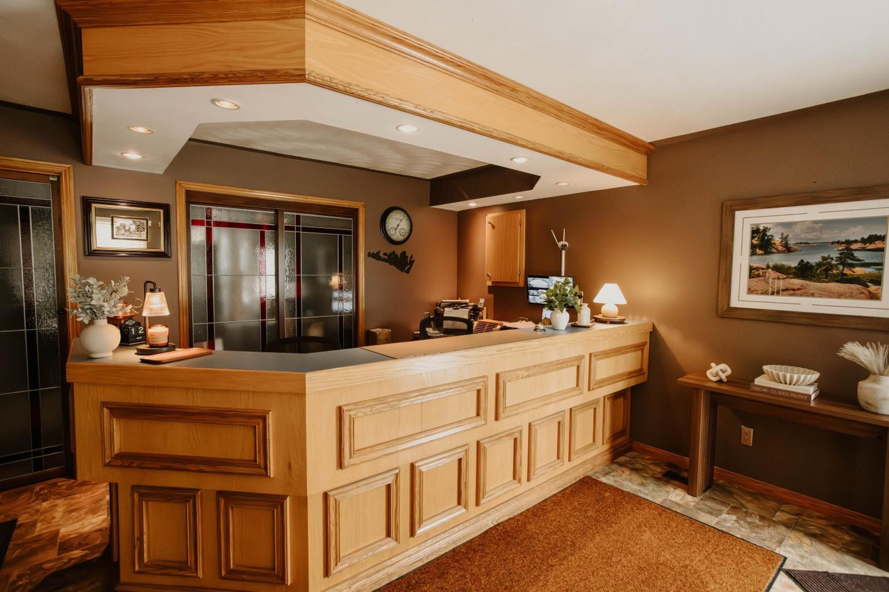 A kitchen with wooden cabinetry, a built-in island, a clock, and a framed landscape painting.
